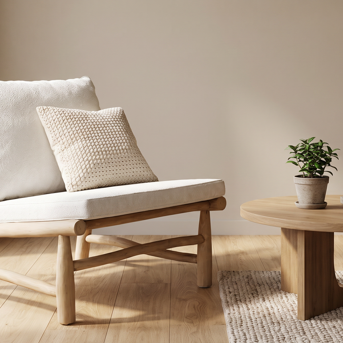 2e-kans houten loungebank met witte kussens in een lichte woonkamer, naast een ronde houten salontafel