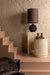 Crème kleurige, ronde bijzettafel van beton met een robuuste textuur, geplaatst in een sfeervol interieur.