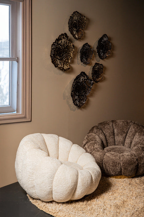 Zandbeige Daisy fauteuil met bloemvormige kuip en goudkleurig onderstel in een sfeervol interieur.