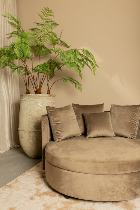 Ronde zandkleurige fauteuil van PTMD met zachte polyester bekleding en bijpassende sierkussens in een modern interieur.