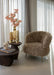 Bruine fauteuil Franklyn van PTMD met aaibare polyester bekleding en een slank metalen onderstel in een sfeervol interieur.