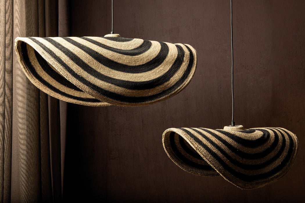 Twee beige en zwarte rotan hanglampen van PTMD met golvende lijnen en een natuurlijk design.