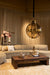 Grote ronde PTMD hanglamp van goudkleurig metaal en glas in een sfeervol interieur.