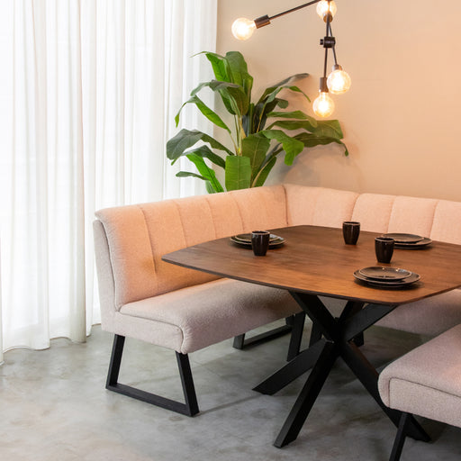 LABEL51 Modula hoekbank in naturel bouclé met zwart metalen frame aan een houten eettafel.