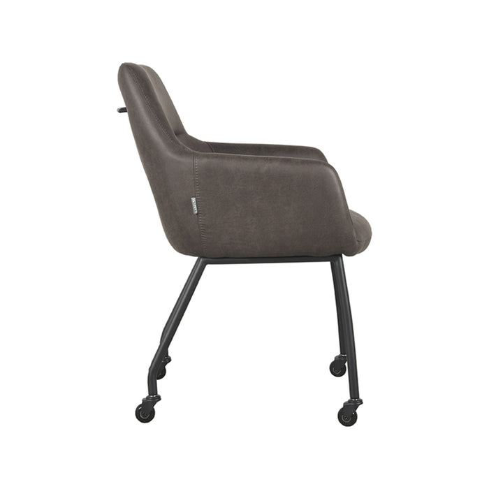 LABEL51 Lenny eetkamerstoel in antraciet micro-suède met armleuningen en zwart metalen frame op wieltjes.