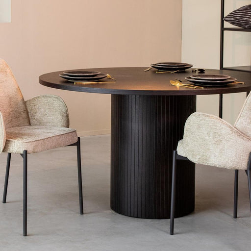Ronde zwarte eiken eettafel Oliva van 130 cm met een geribbelde kolomvoet en twee gestoffeerde eetkamerstoelen.