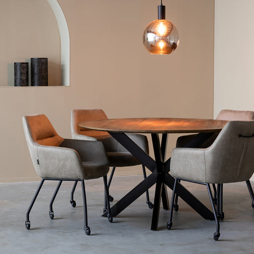 Ronde LABEL51 Otis eettafel van 130 cm met glad mangohouten blad en zwart metalen kruispoot in een modern interieur.