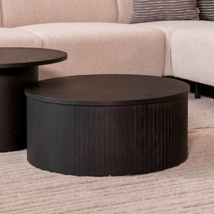 Ronde zwarte salontafel Oliva van 70 cm met een stijlvol geribbeld houten design in een modern interieur.