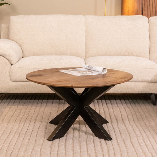 Ronde salontafel Otis van 80 cm met mangohouten blad en zwart metalen kruispoot in een sfeervol interieur.
